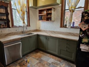 warm green kitchen cabinets Pittsburgh renovation 2026 with natural stone countertop